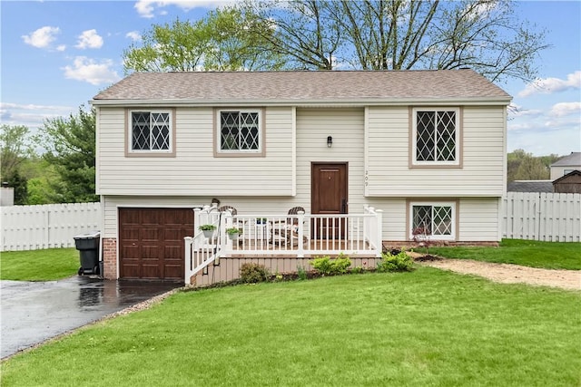 split foyer home featuring fence, an attached garage, driveway, and a front yard