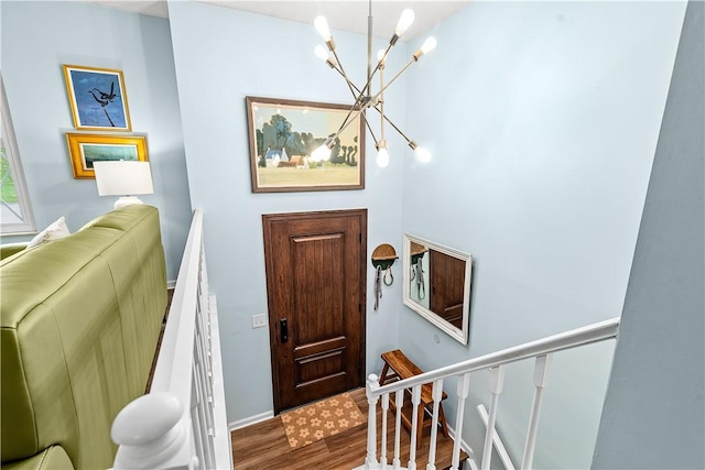 entryway with baseboards, wood finished floors, and a chandelier
