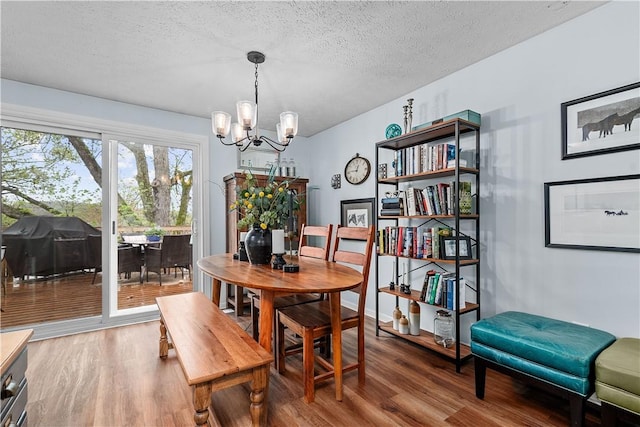 dining space with a textured ceiling, an inviting chandelier, and wood finished floors