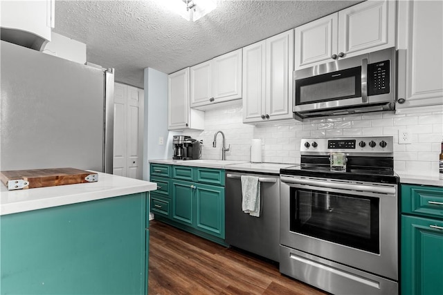 kitchen with a sink, white cabinets, stainless steel appliances, and dark wood-style flooring