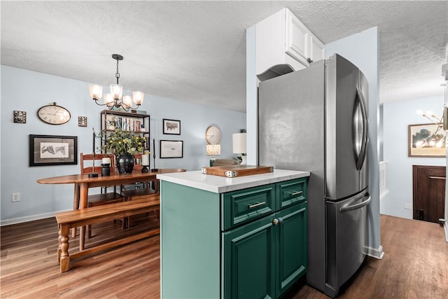 kitchen featuring freestanding refrigerator, wood finished floors, a textured ceiling, a chandelier, and green cabinets