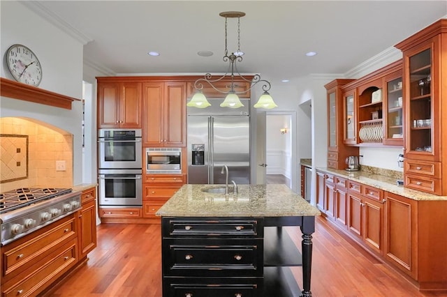 kitchen featuring a sink, built in appliances, ornamental molding, and light stone counters
