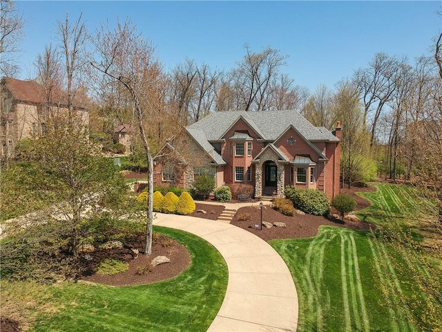 craftsman-style home with brick siding, a chimney, and a front yard