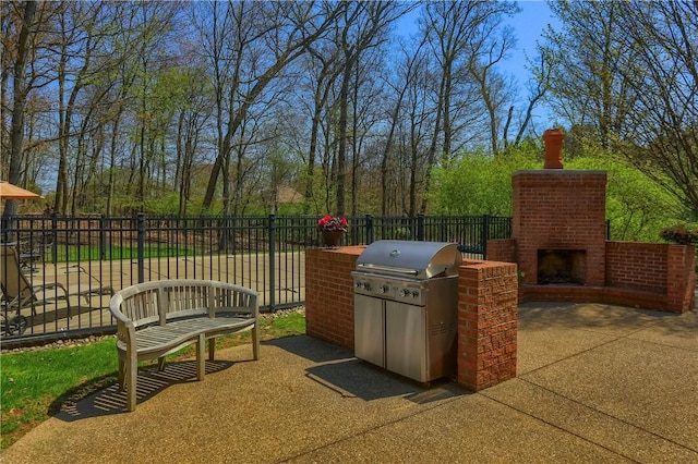view of patio with a grill, fence, and an outdoor brick fireplace