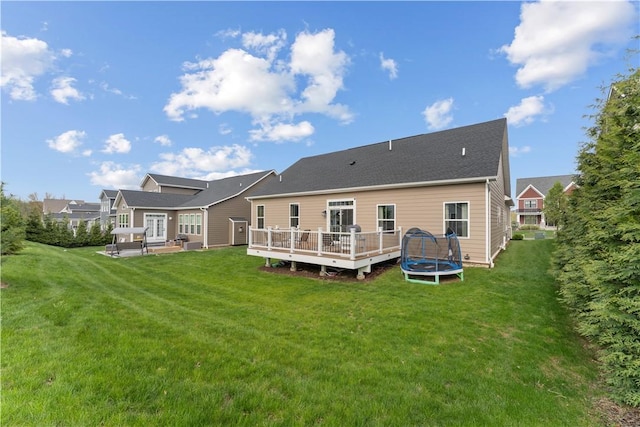 back of house featuring a patio, a trampoline, a wooden deck, and a yard