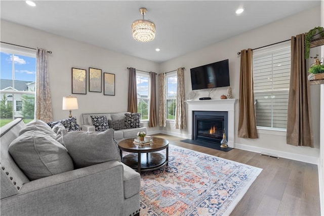 living area with visible vents, a fireplace with flush hearth, baseboards, and wood finished floors