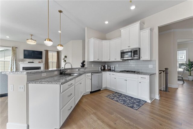 kitchen featuring a sink, light stone counters, stainless steel appliances, and a healthy amount of sunlight