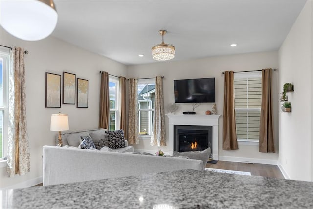 living room featuring recessed lighting, baseboards, a glass covered fireplace, and wood finished floors