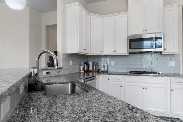 kitchen featuring a sink, dark stone counters, white cabinets, and stainless steel appliances