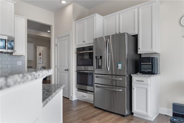 kitchen with decorative backsplash, light wood-style flooring, white cabinets, and stainless steel appliances