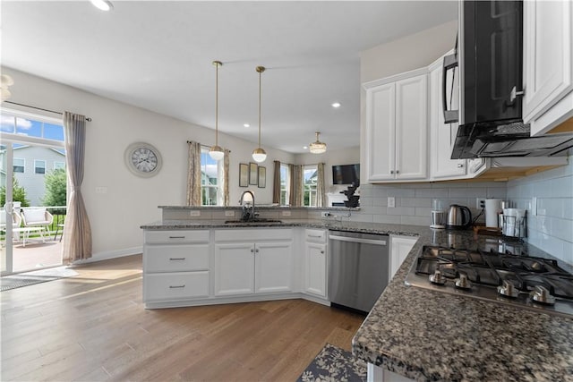 kitchen featuring a sink, stainless steel appliances, white cabinetry, a peninsula, and decorative backsplash