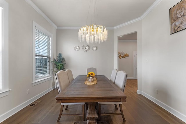 dining room with an inviting chandelier, baseboards, crown molding, and wood finished floors