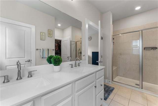 full bath with a sink, tile patterned floors, a stall shower, and double vanity