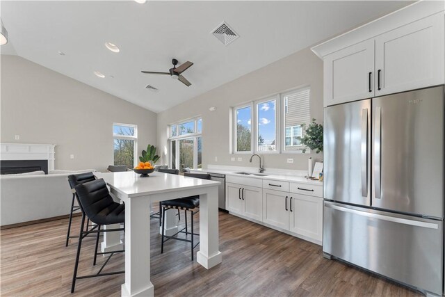 kitchen with visible vents, lofted ceiling, a breakfast bar, a sink, and stainless steel appliances