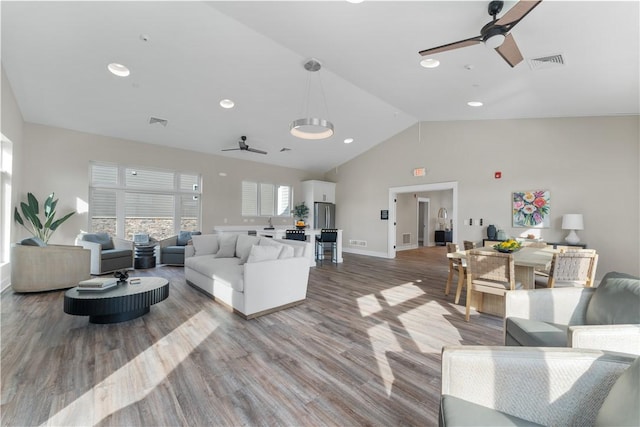 living room featuring visible vents, a ceiling fan, baseboards, and wood finished floors