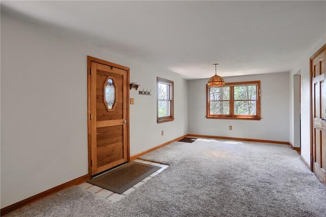 foyer entrance with plenty of natural light, carpet flooring, and baseboards