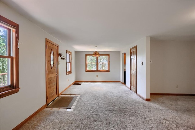 foyer entrance featuring light colored carpet and baseboards