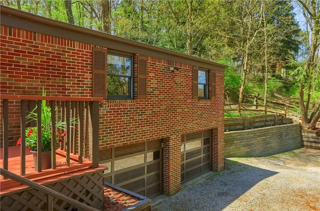 view of home's exterior with brick siding, a garage, and gravel driveway
