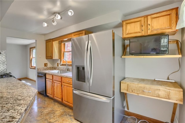 kitchen featuring baseboards, a sink, light stone counters, and black appliances