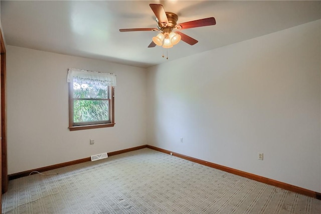 spare room with visible vents, a ceiling fan, baseboards, and light colored carpet