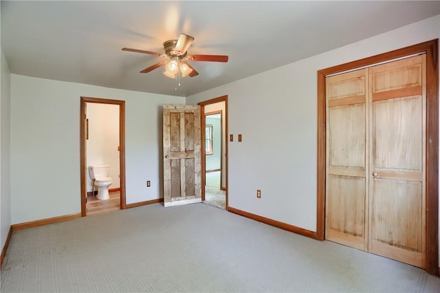unfurnished bedroom with a closet, baseboards, ceiling fan, connected bathroom, and carpet