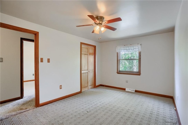 empty room featuring a ceiling fan, baseboards, visible vents, and light carpet