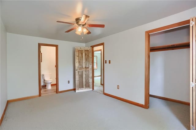 unfurnished bedroom featuring carpet floors, a ceiling fan, baseboards, ensuite bathroom, and a closet