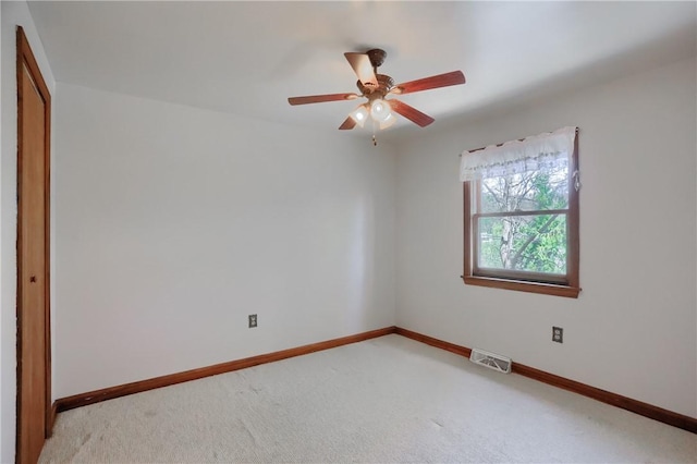 empty room with light colored carpet, baseboards, visible vents, and ceiling fan