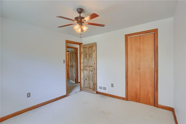 unfurnished bedroom with a closet, visible vents, light carpet, baseboards, and ceiling fan