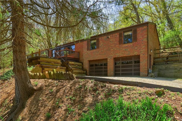 view of front facade with an attached garage, a wooden deck, and brick siding