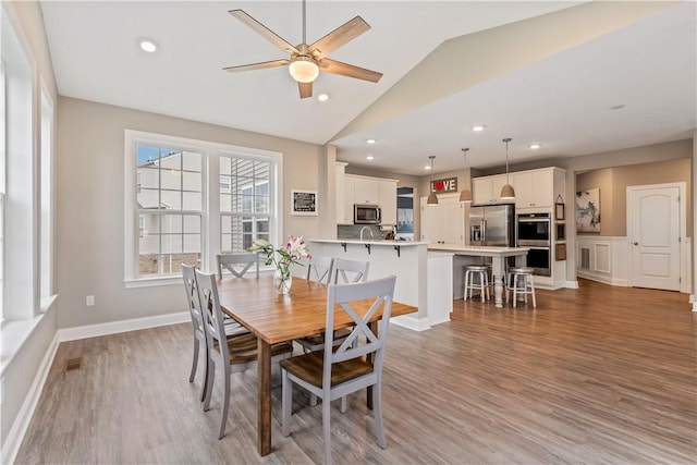 dining room with ceiling fan, vaulted ceiling, recessed lighting, and wood finished floors