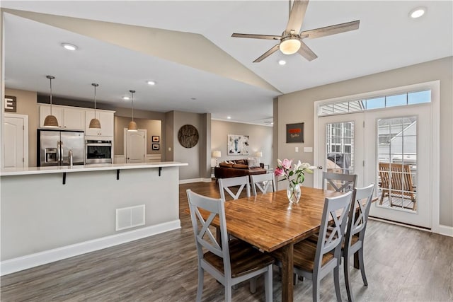 dining space with dark wood-style flooring, a ceiling fan, vaulted ceiling, and visible vents
