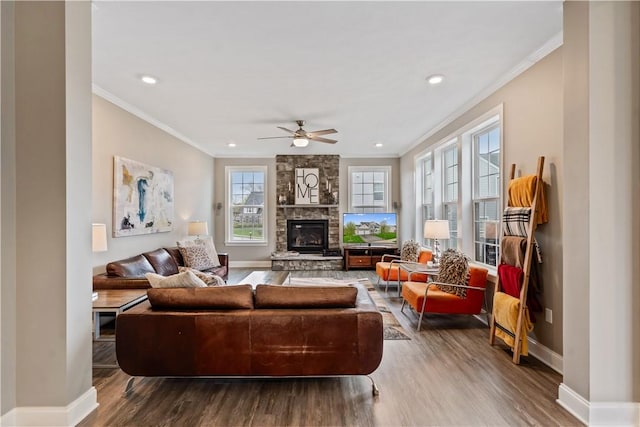 living room with baseboards, ornamental molding, a ceiling fan, and wood finished floors