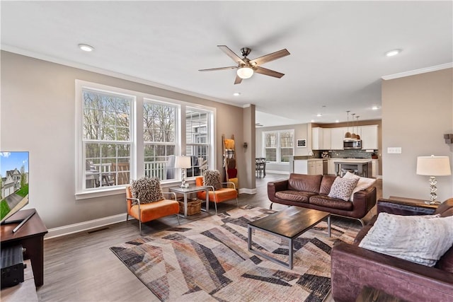 living room with ornamental molding, wood finished floors, baseboards, ceiling fan, and recessed lighting
