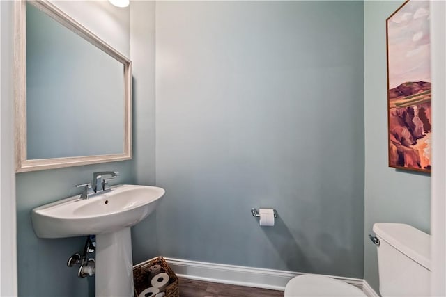 bathroom with baseboards, wood finished floors, and toilet