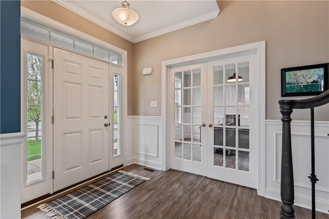 entrance foyer with french doors, wainscoting, dark wood finished floors, ornamental molding, and a decorative wall