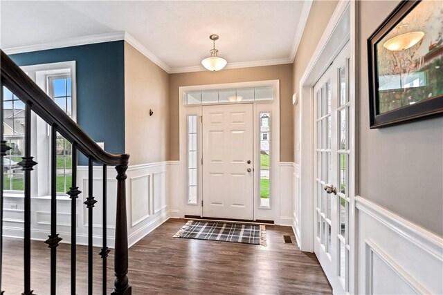 entryway with crown molding, wainscoting, a decorative wall, stairs, and dark wood-style floors