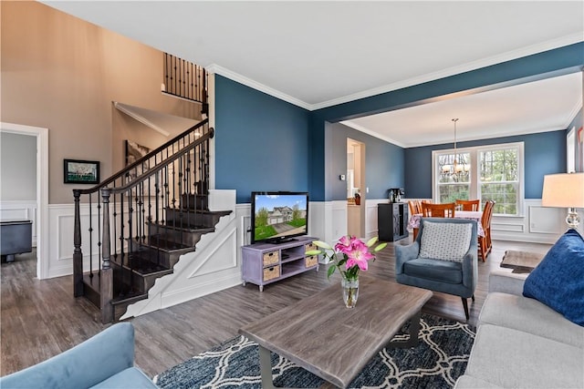 living room with an inviting chandelier, crown molding, stairs, and wood finished floors