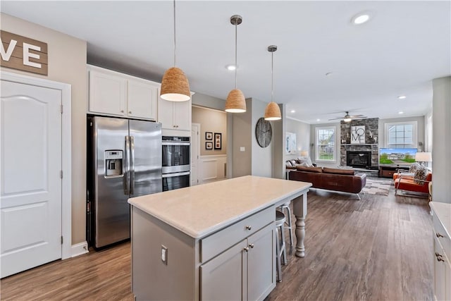 kitchen with white cabinets, ceiling fan, appliances with stainless steel finishes, dark wood finished floors, and a center island