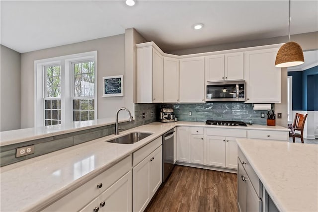 kitchen featuring decorative backsplash, appliances with stainless steel finishes, a sink, white cabinets, and dark wood-style floors