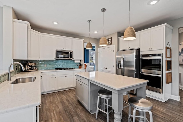 kitchen with dark wood-type flooring, white cabinetry, tasteful backsplash, a sink, and stainless steel appliances