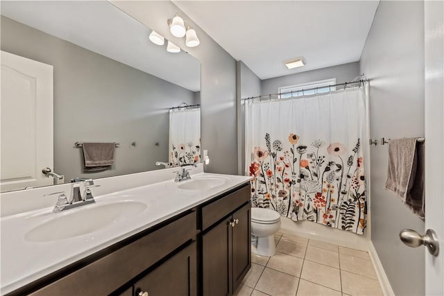 full bathroom with double vanity, a sink, tile patterned floors, and toilet
