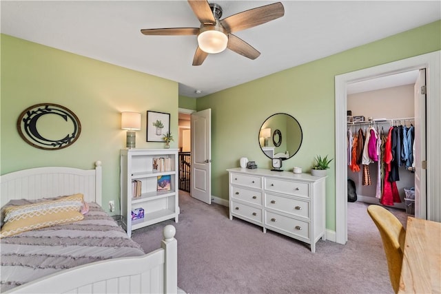 bedroom with a closet, a ceiling fan, baseboards, a walk in closet, and carpet flooring