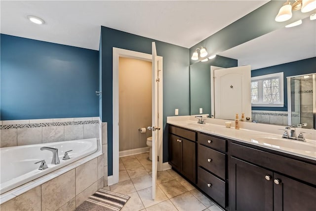 bathroom featuring a garden tub, double vanity, toilet, a shower stall, and a sink