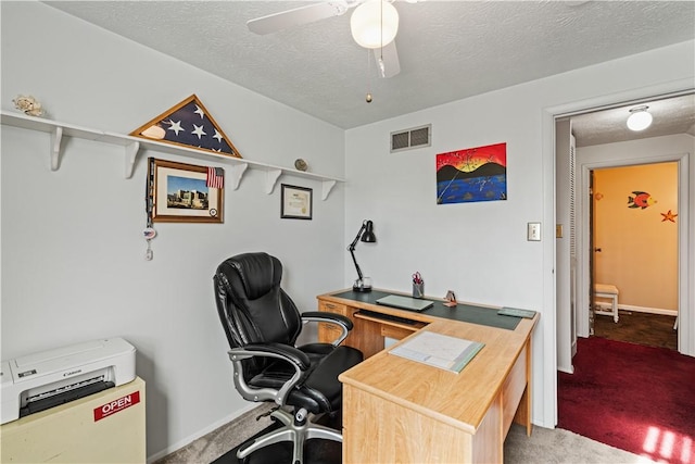 home office with carpet floors, a textured ceiling, and visible vents
