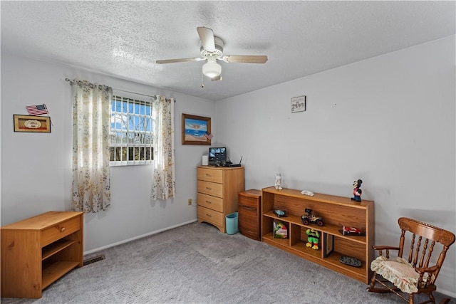 interior space featuring carpet flooring, a textured ceiling, a ceiling fan, baseboards, and visible vents
