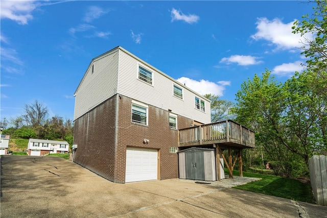 back of house with a garage, brick siding, concrete driveway, a storage shed, and an outbuilding