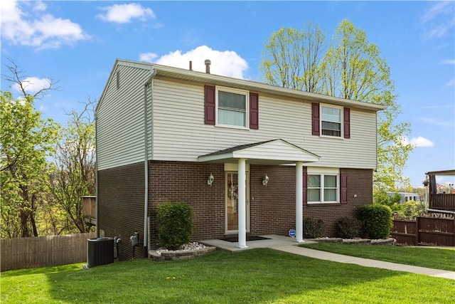 view of front of property with brick siding, central AC unit, fence, and a front yard