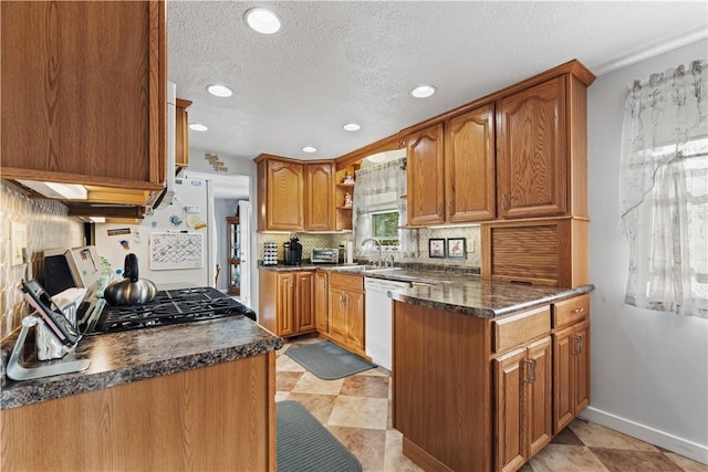 kitchen with a textured ceiling, decorative backsplash, a sink, and dishwasher