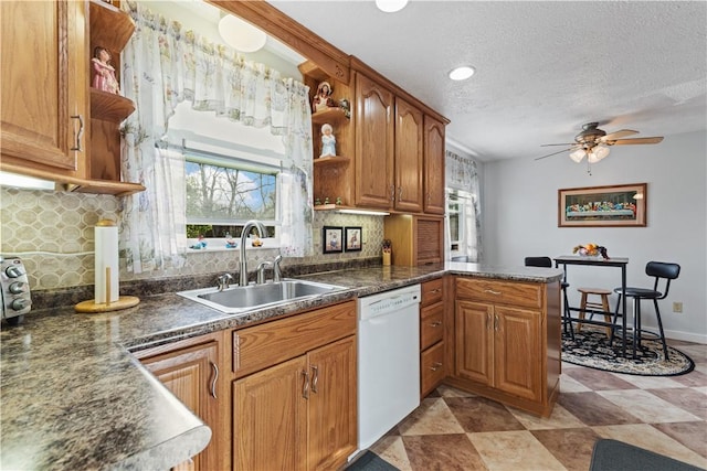 kitchen with white dishwasher, open shelves, decorative backsplash, and a sink